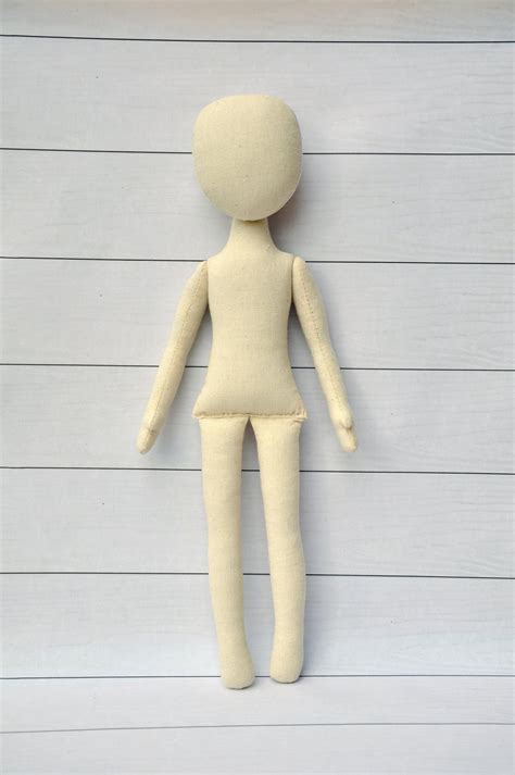 The face portion is devoid of facial features and is formed with slight concave depressions suggesting the location of eyes and a mouth. . Blank doll